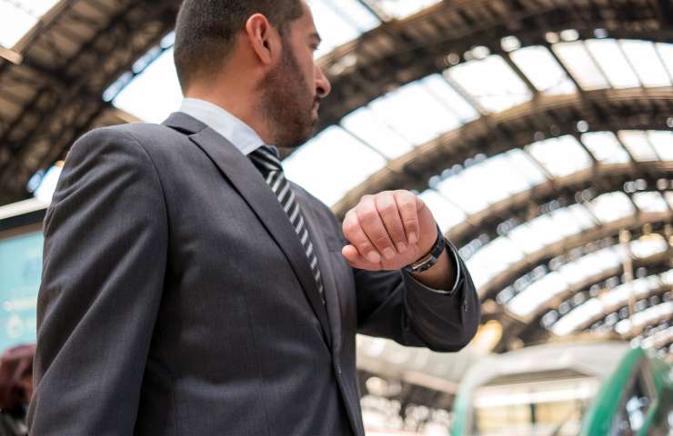 uomo guarda orologio e in stazione